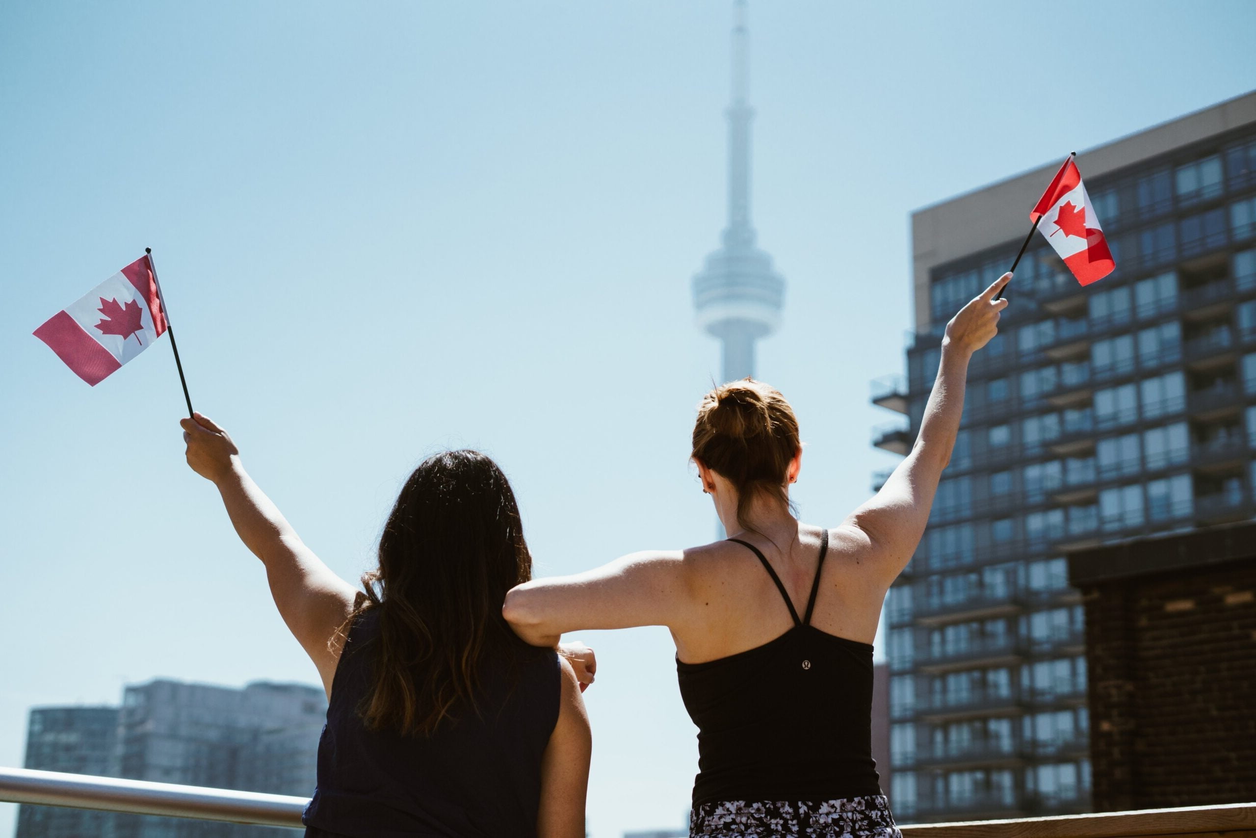 Women hold up Canadian flags, free public domain travel CC0 photo.